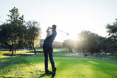 A golfer making a powerful tee-off shot on a bright golf course, capturing the energy of the game.